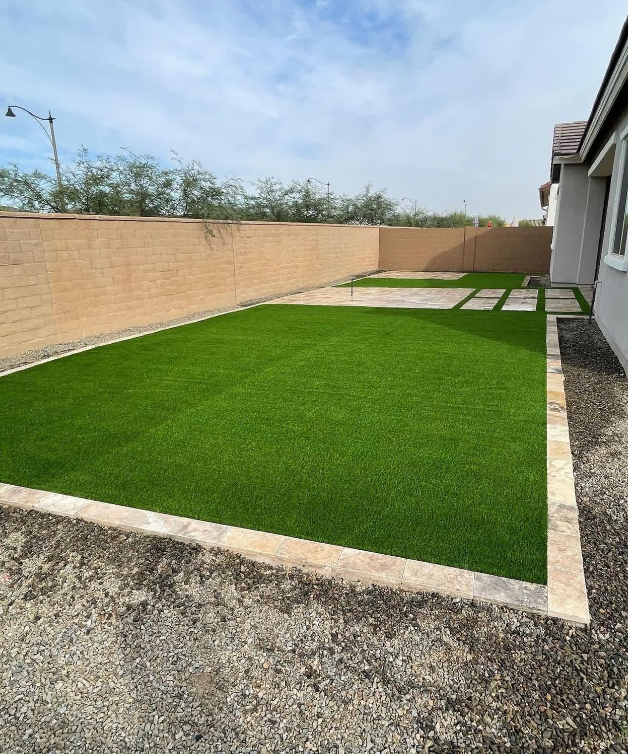 A backyard with a lush green lawn and a brick wall.