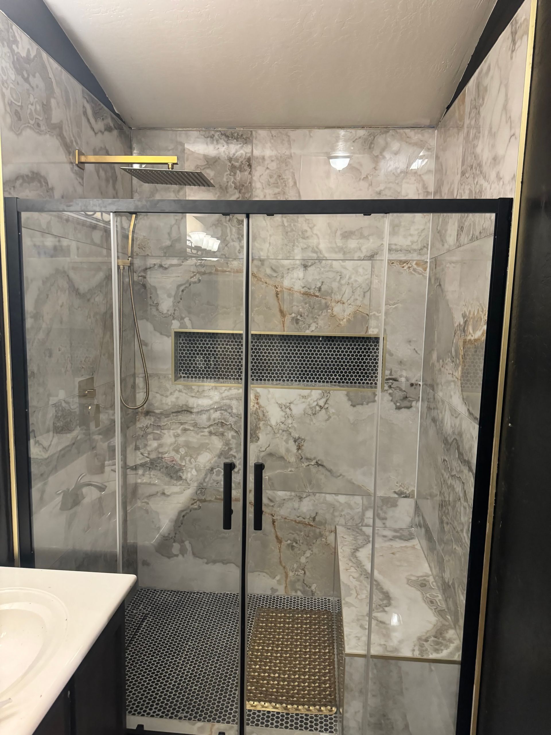 A bathroom with a walk in shower and a sink.