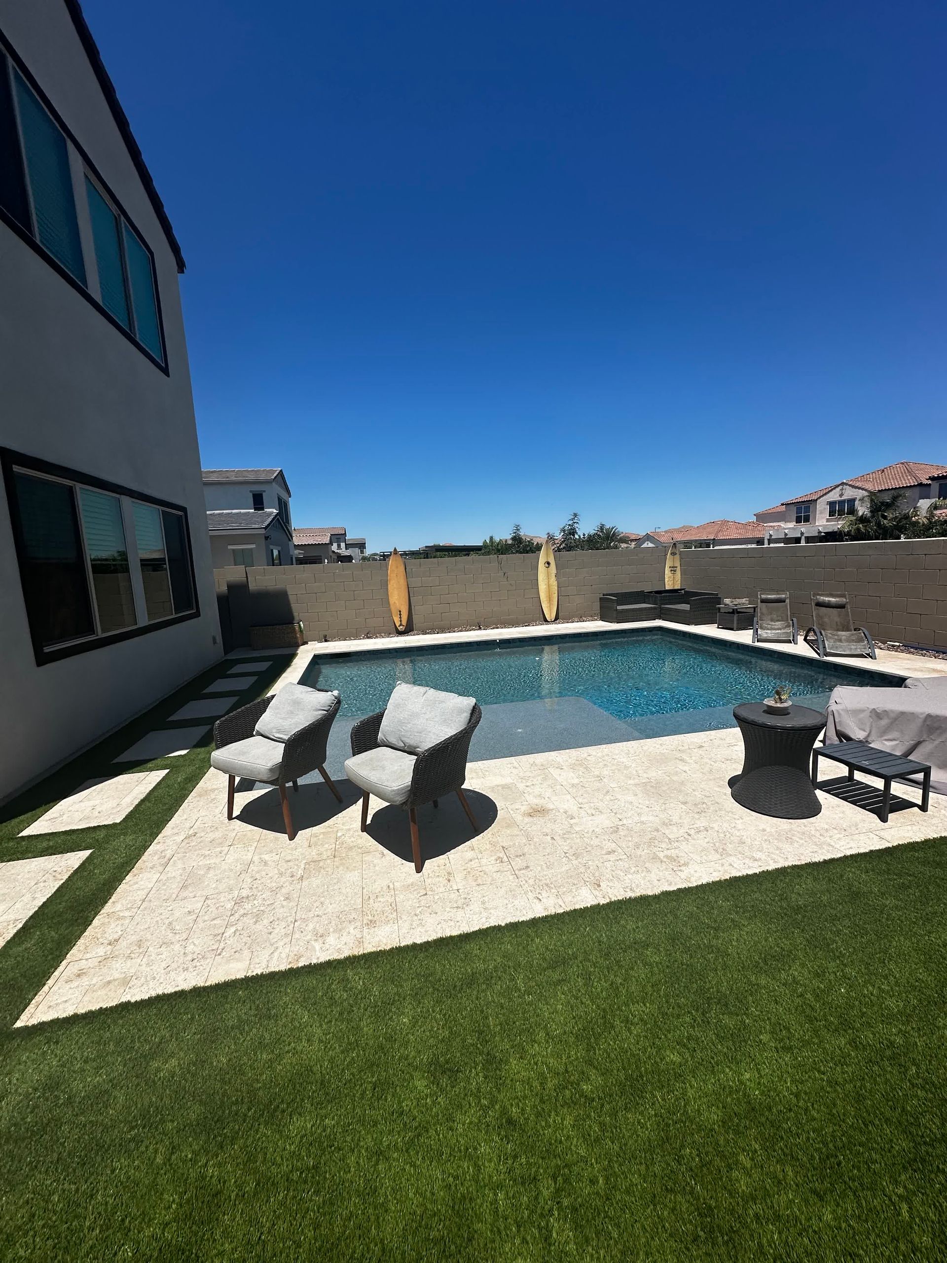 There is a large swimming pool in the backyard of a house.