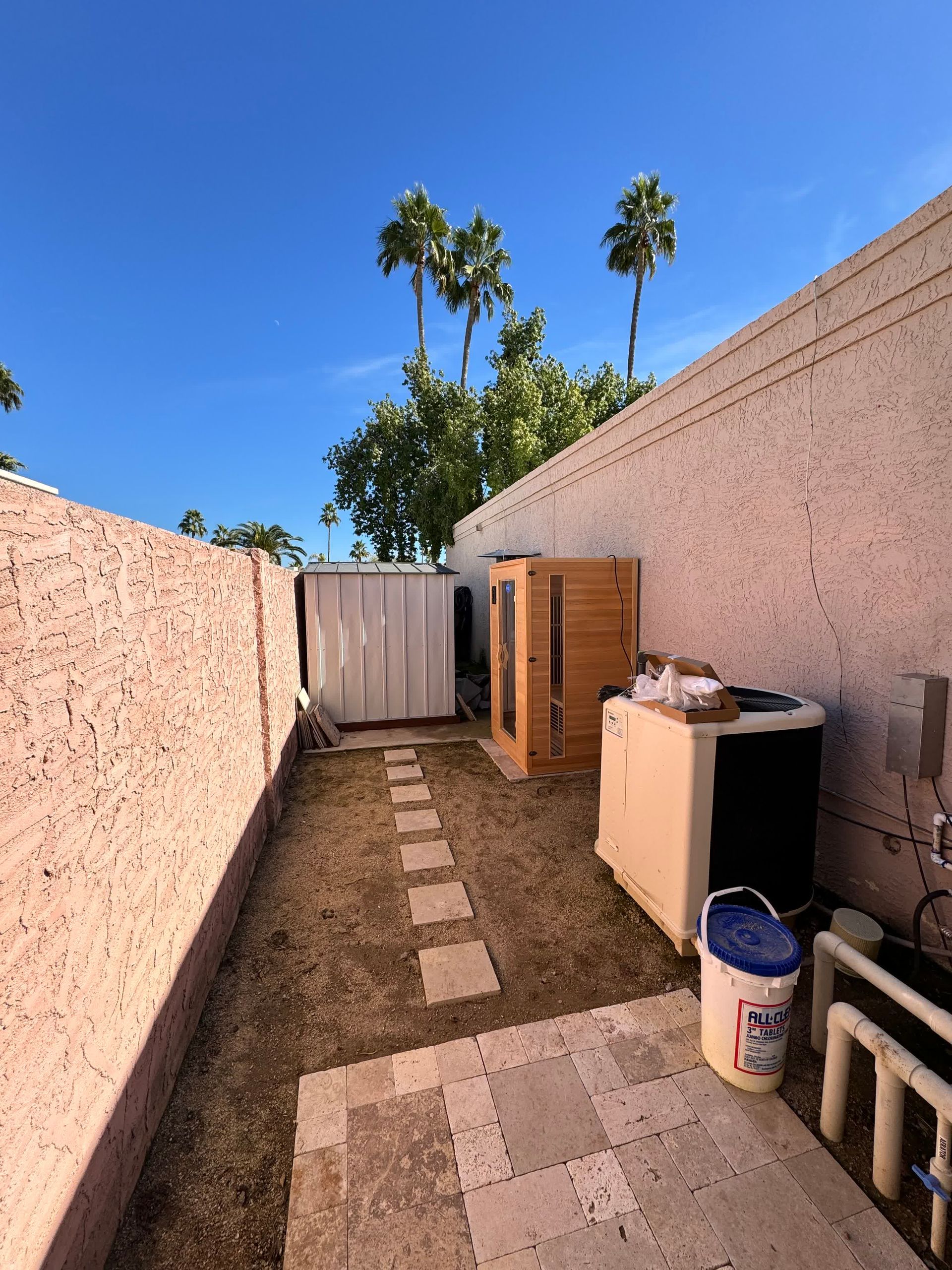 A backyard with a bucket and a few appliances in it.