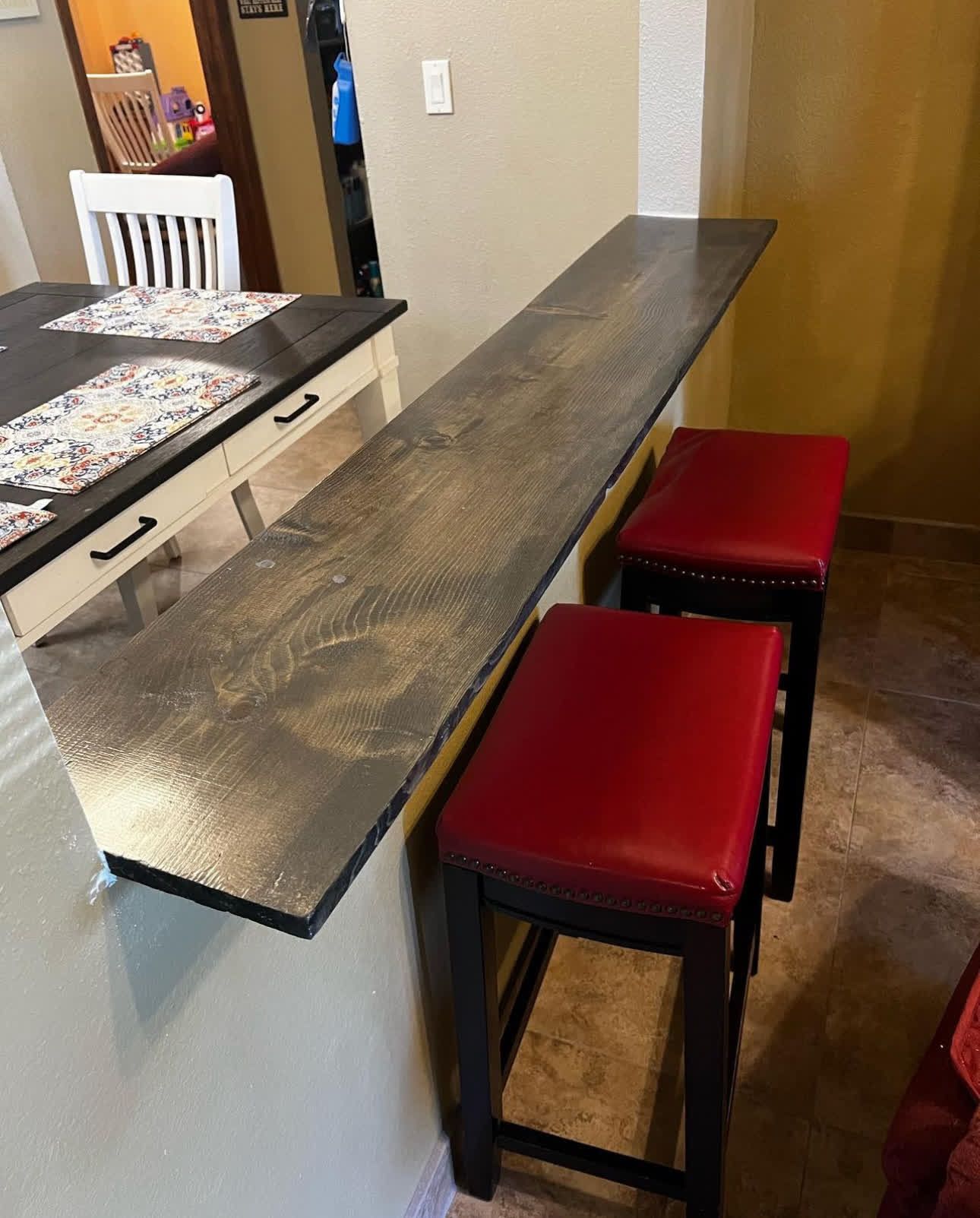 A kitchen with a table and two red stools