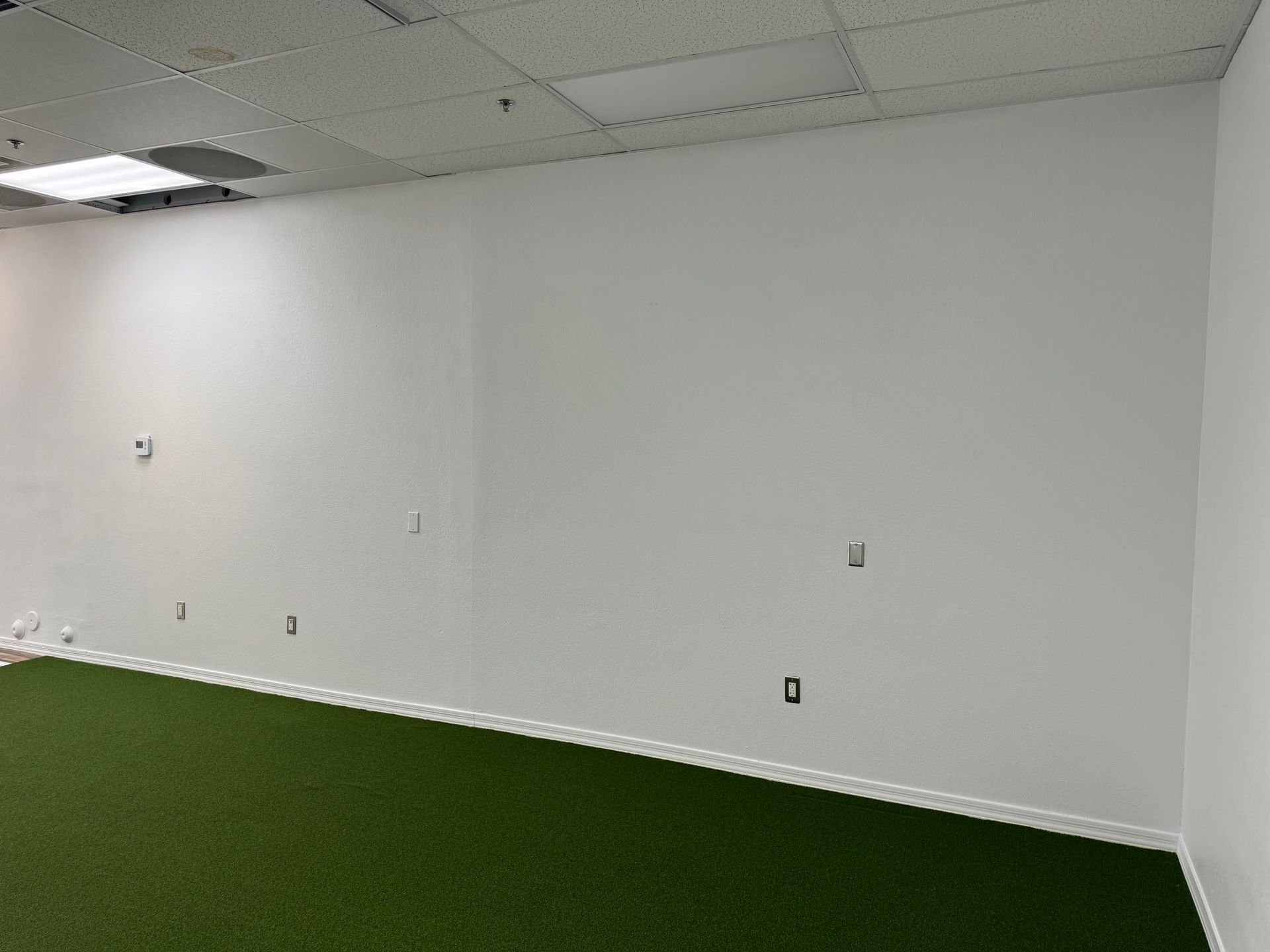 An empty room with a green carpet and white walls.