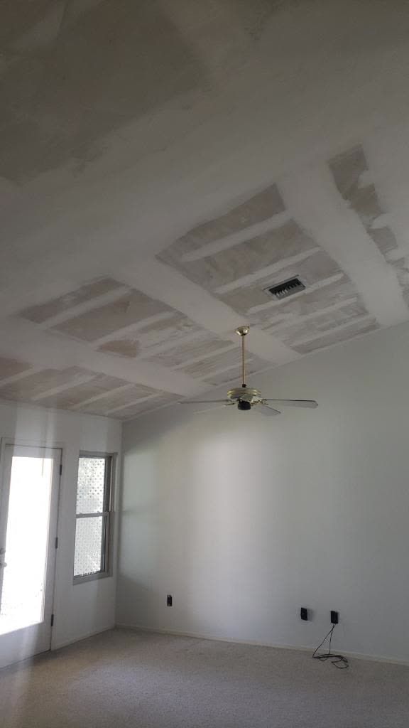 An empty room with a ceiling fan and a window.