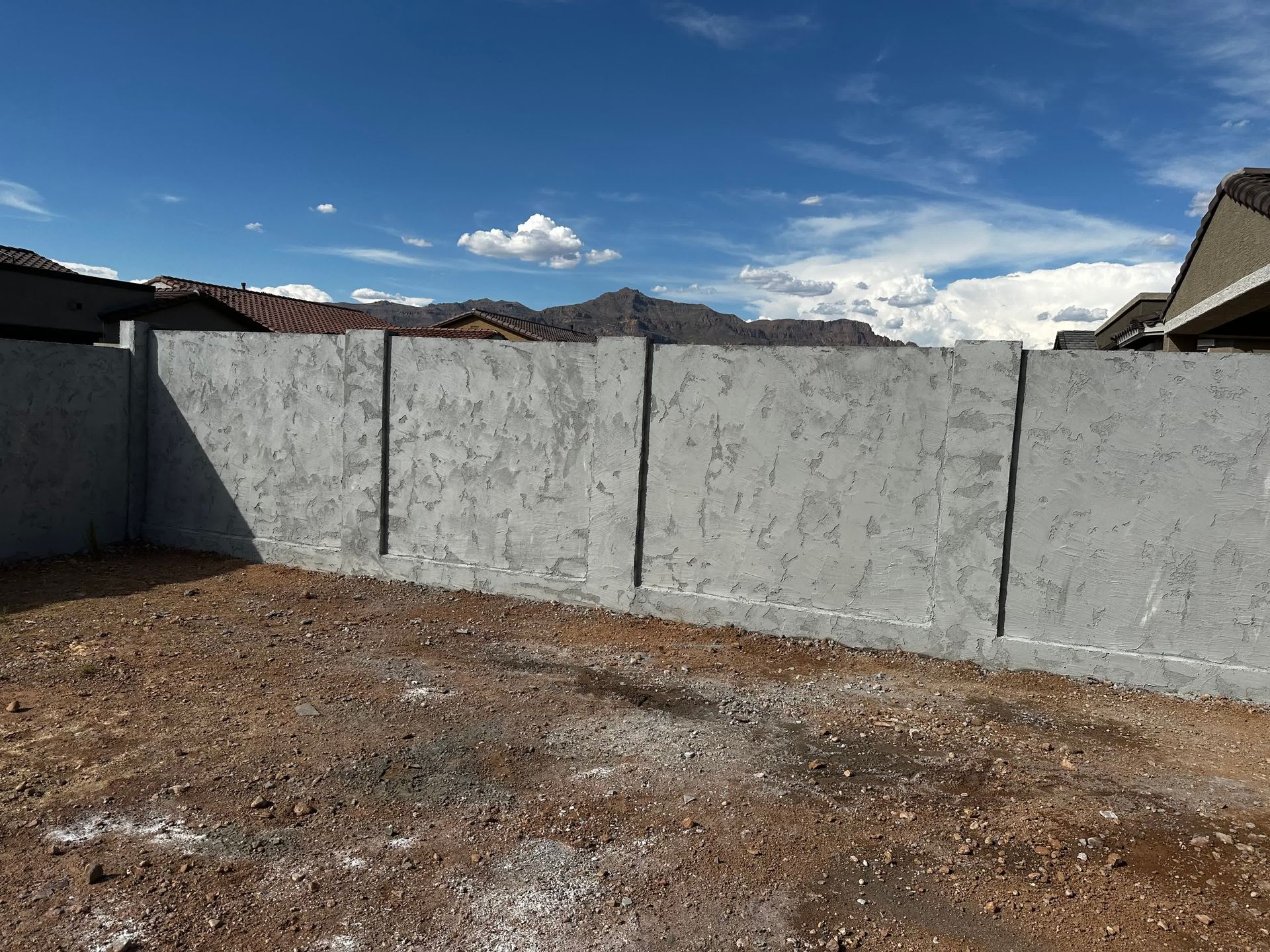 A concrete fence is sitting in the middle of a dirt field.