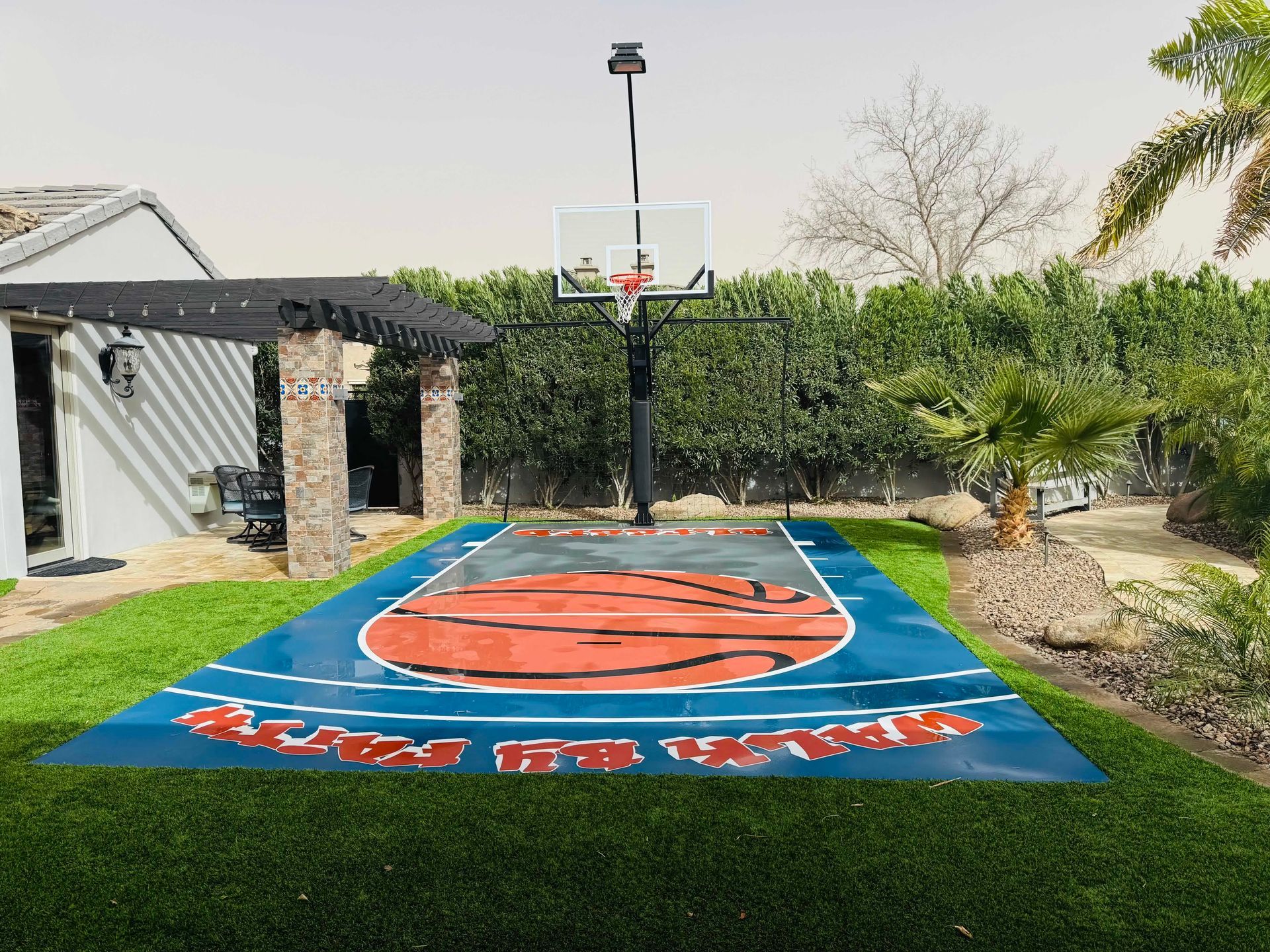 There is a basketball court in the backyard of a house.