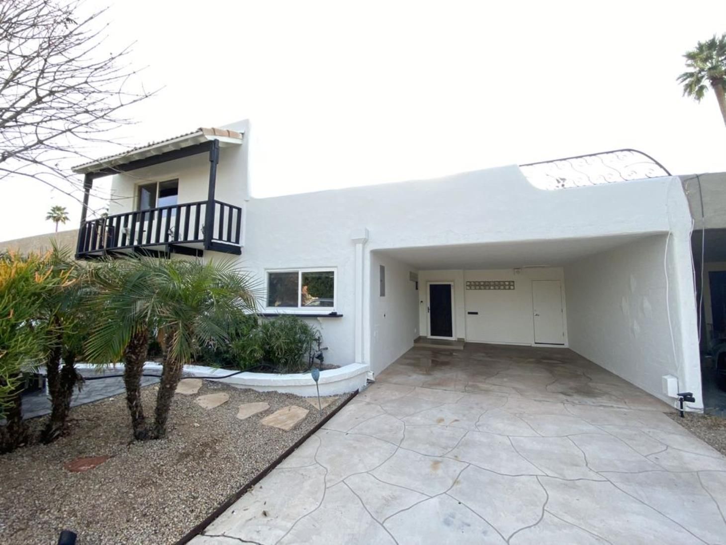 A white house with a carport and a balcony.