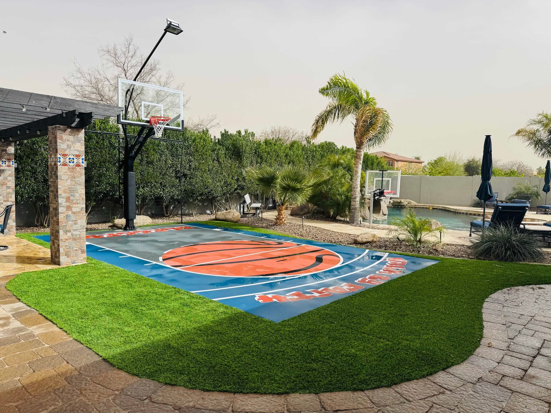 There is a basketball court in the backyard of a house.