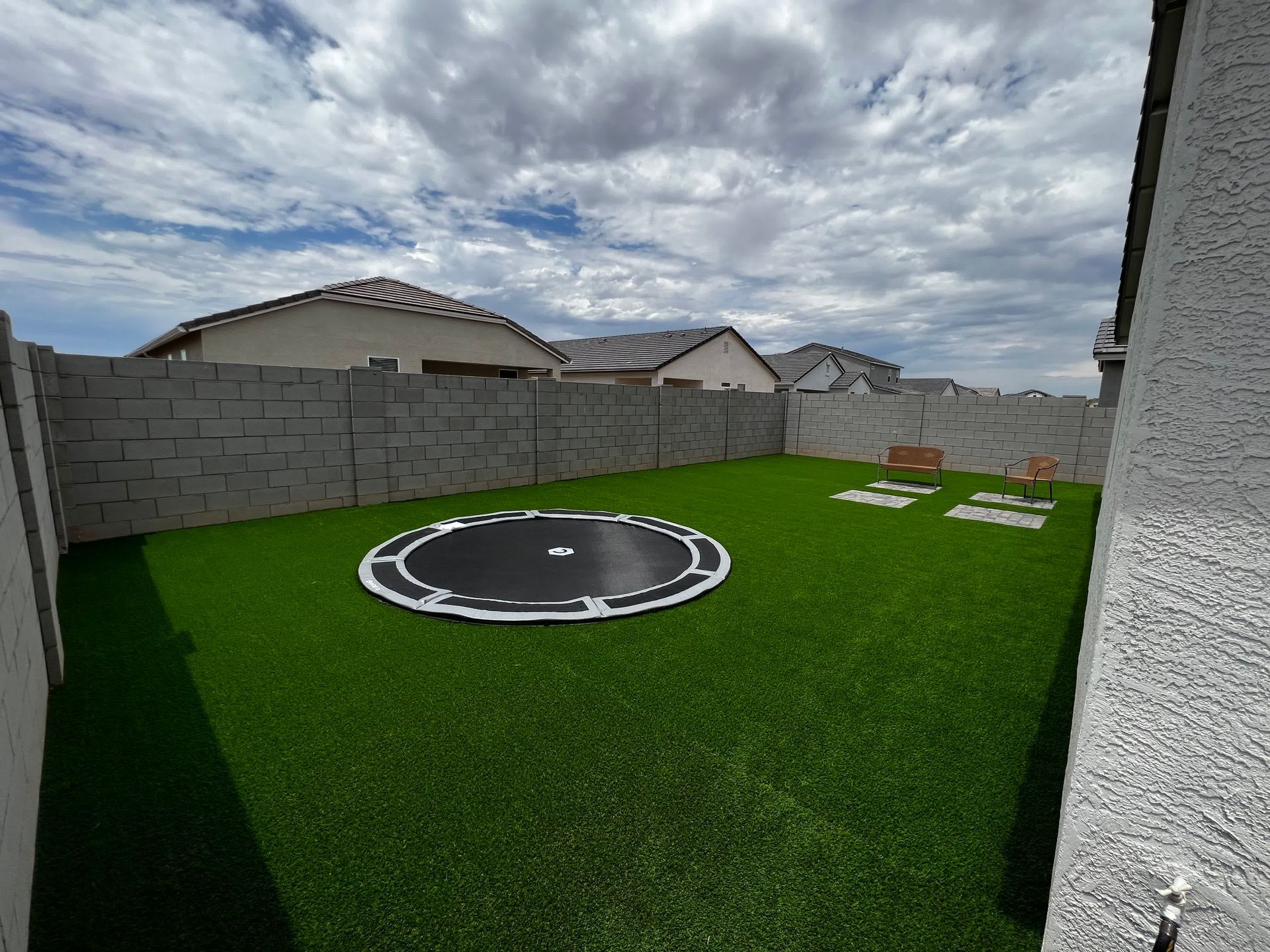 A trampoline is sitting on top of a lush green lawn in a backyard.