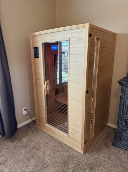 A wooden sauna is sitting in the corner of a bedroom.