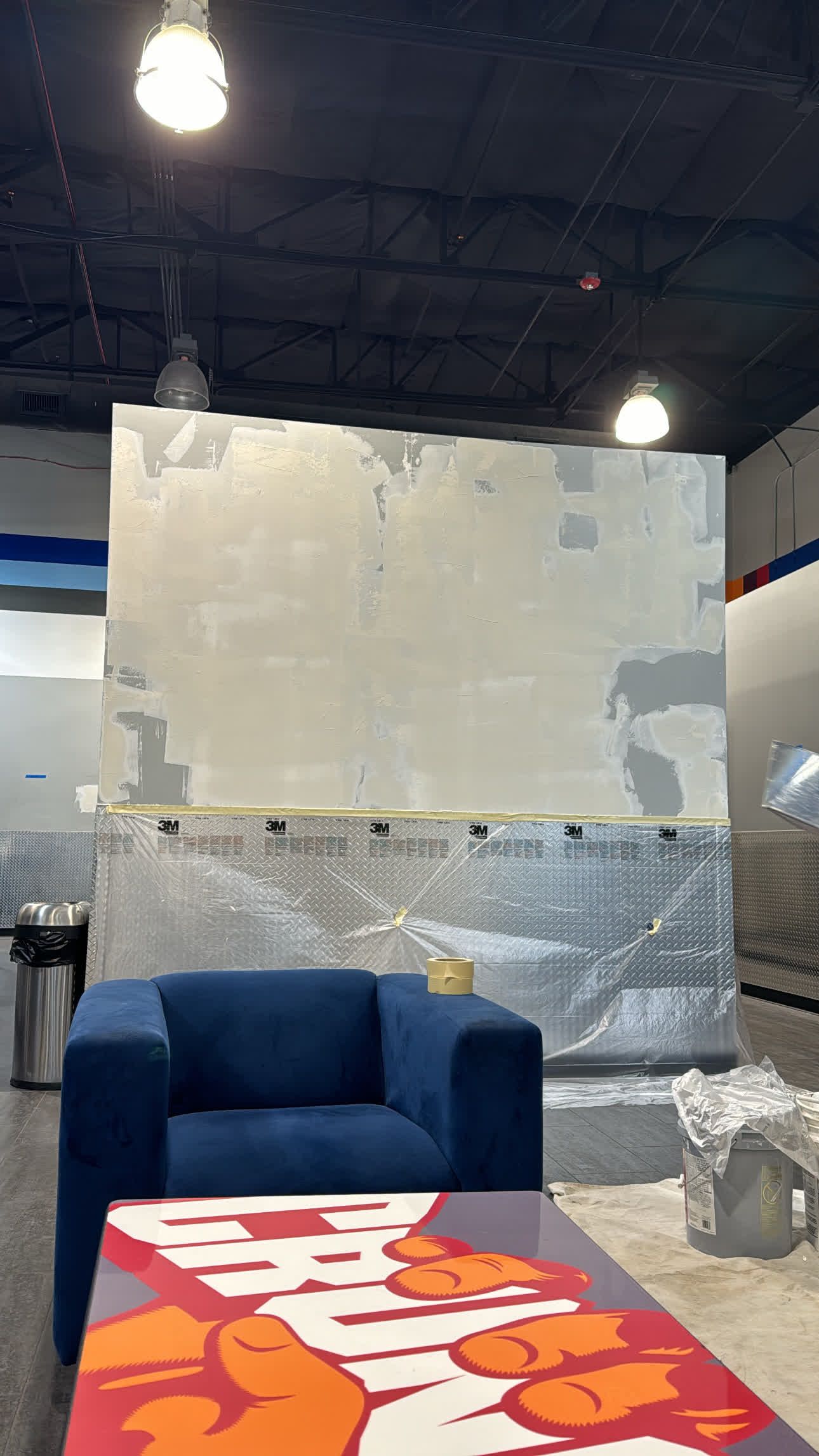 A blue chair is sitting in a room with a table and a wall covered in bubble wrap.
