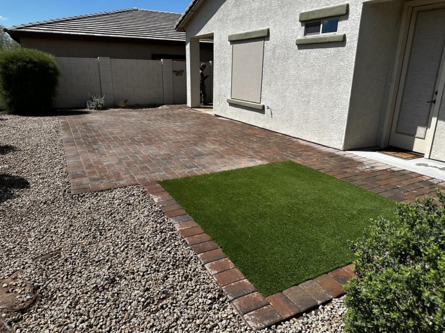 A house with a brick patio and a rug in front of it.