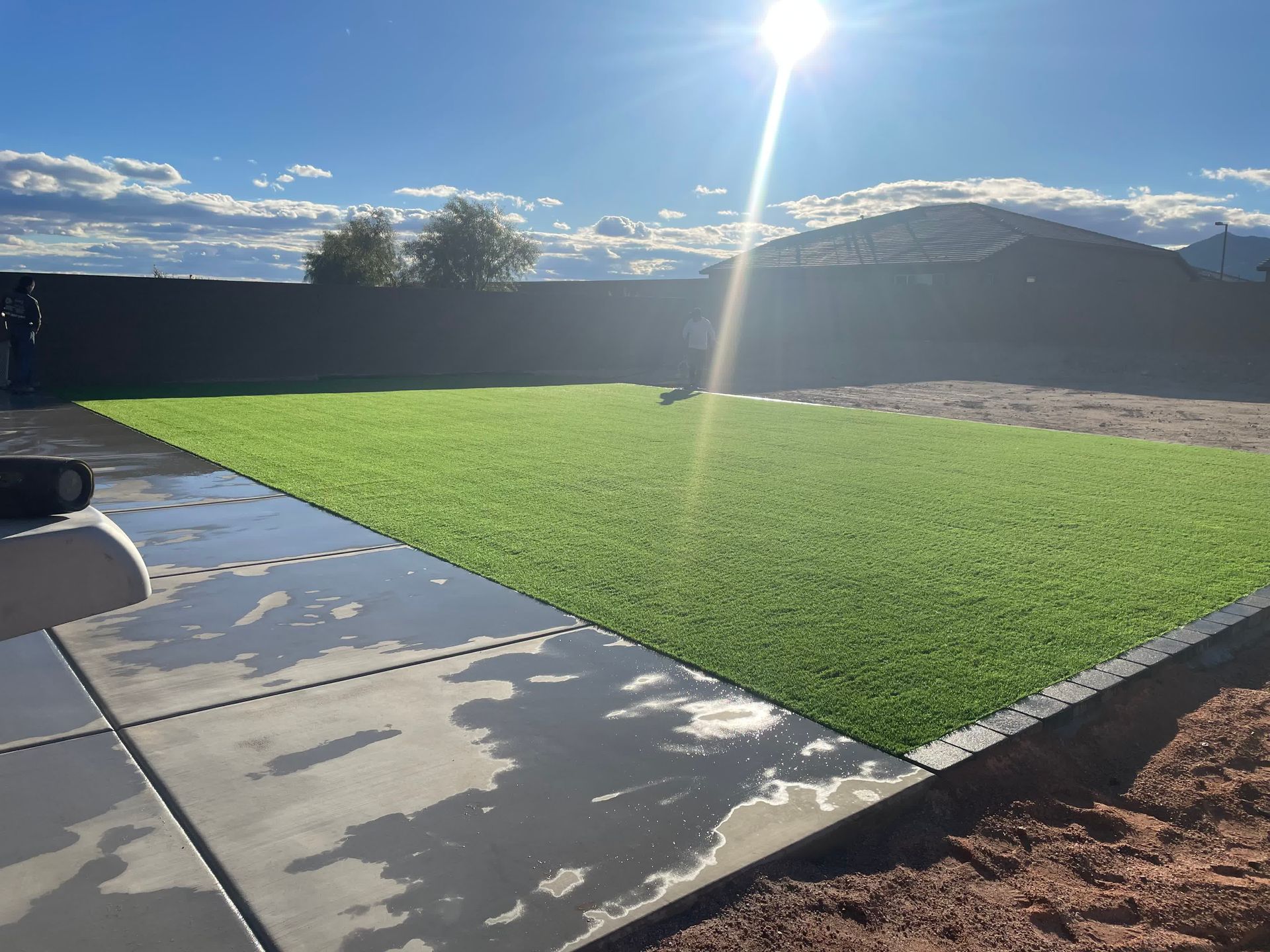 The sun is shining through the clouds over a lush green field.