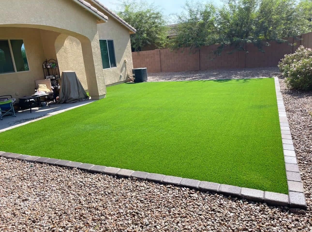 A backyard with a lot of green grass and a house in the background.