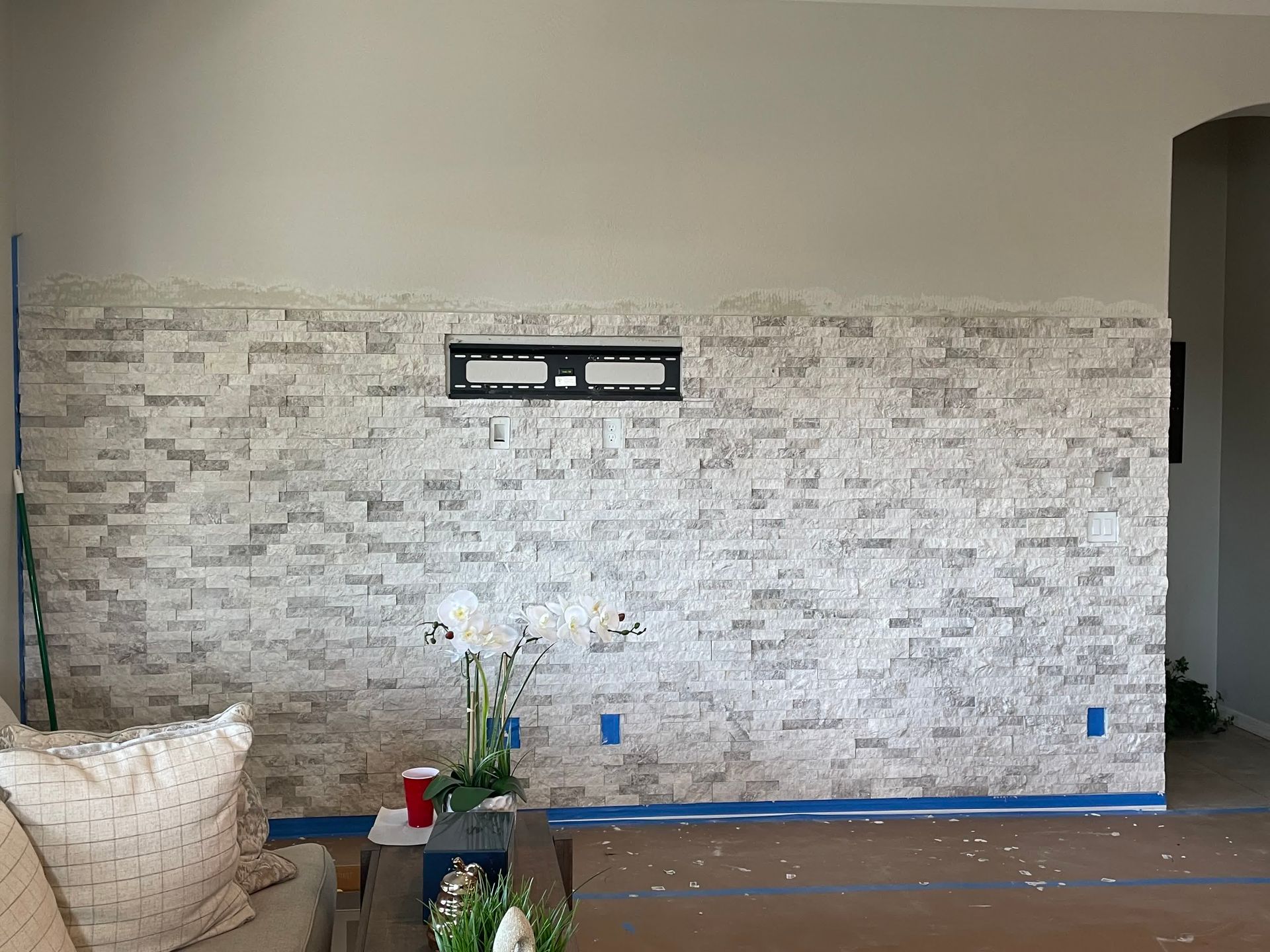 A living room with a brick wall and a flat screen tv mounted on it.