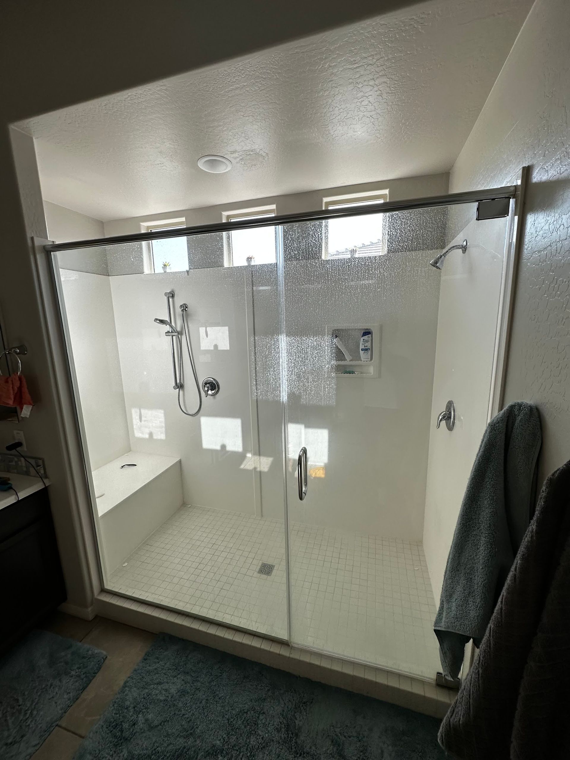 A bathroom with a walk in shower with a glass door.