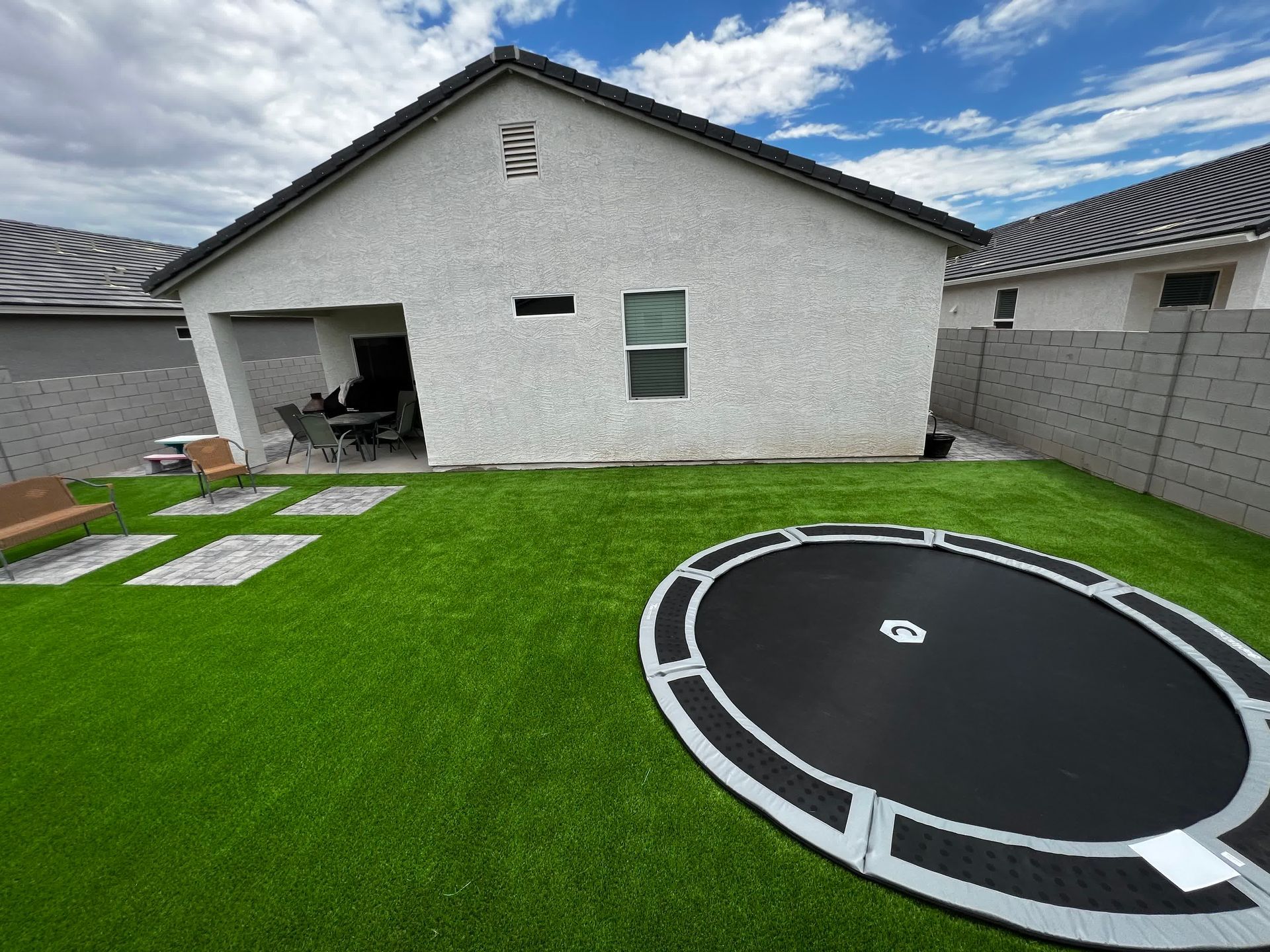 A trampoline is sitting on top of a lush green lawn in front of a house.