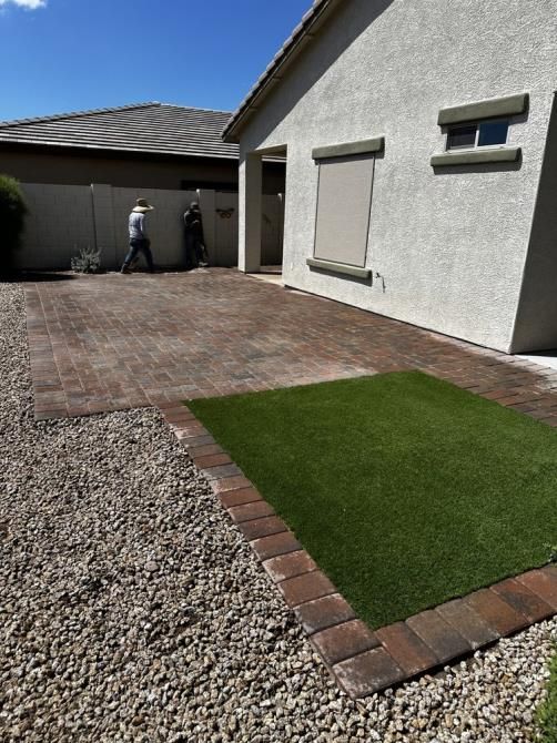 A house with a brick driveway and grass in front of it