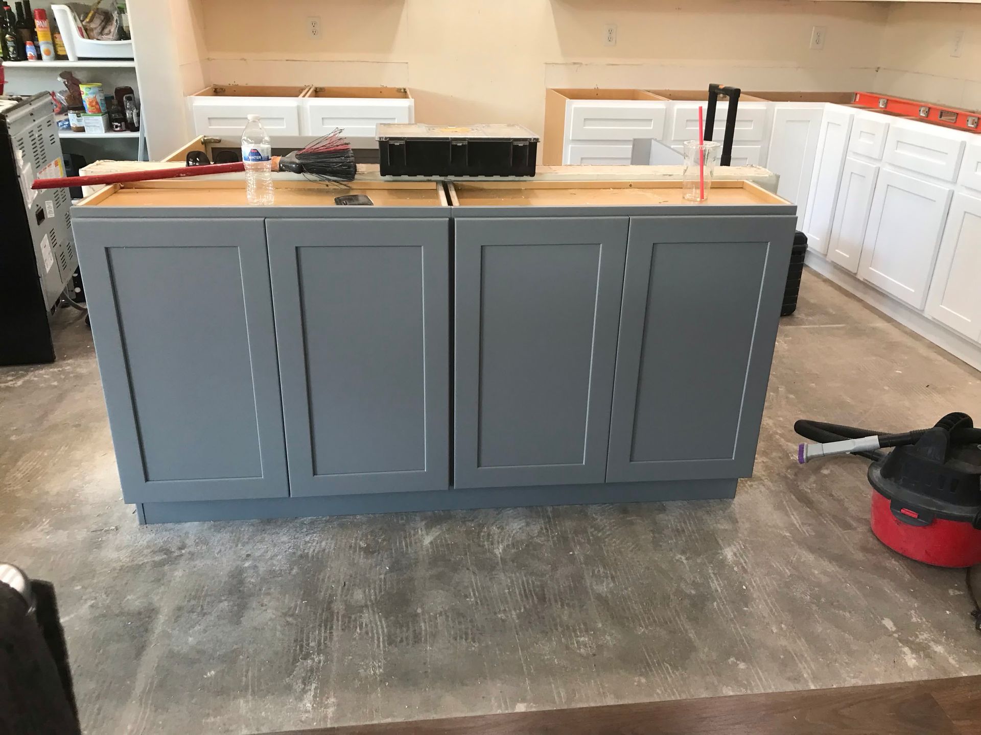 A kitchen is being remodeled with gray cabinets and white cabinets.