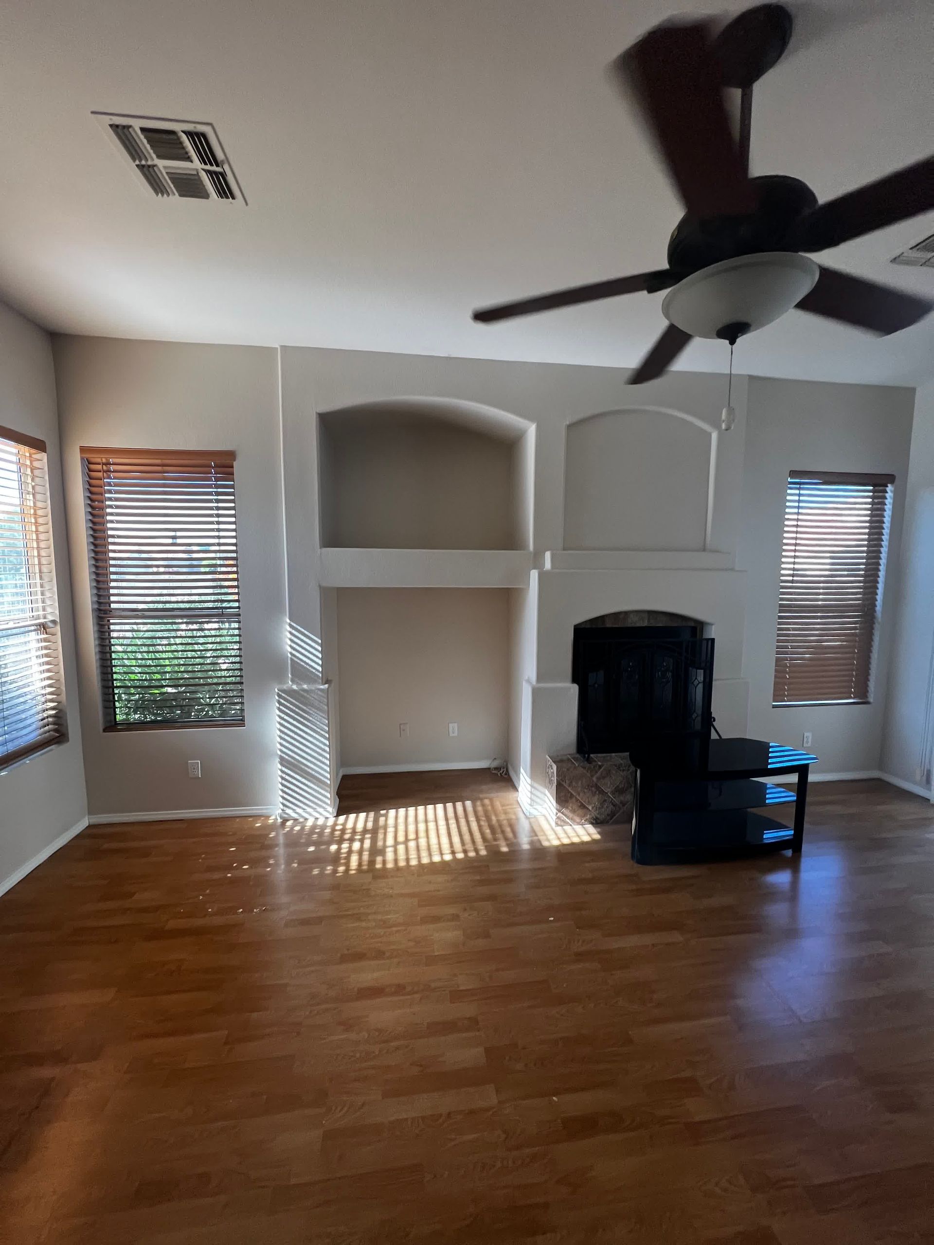 An empty living room with hardwood floors and a ceiling fan.