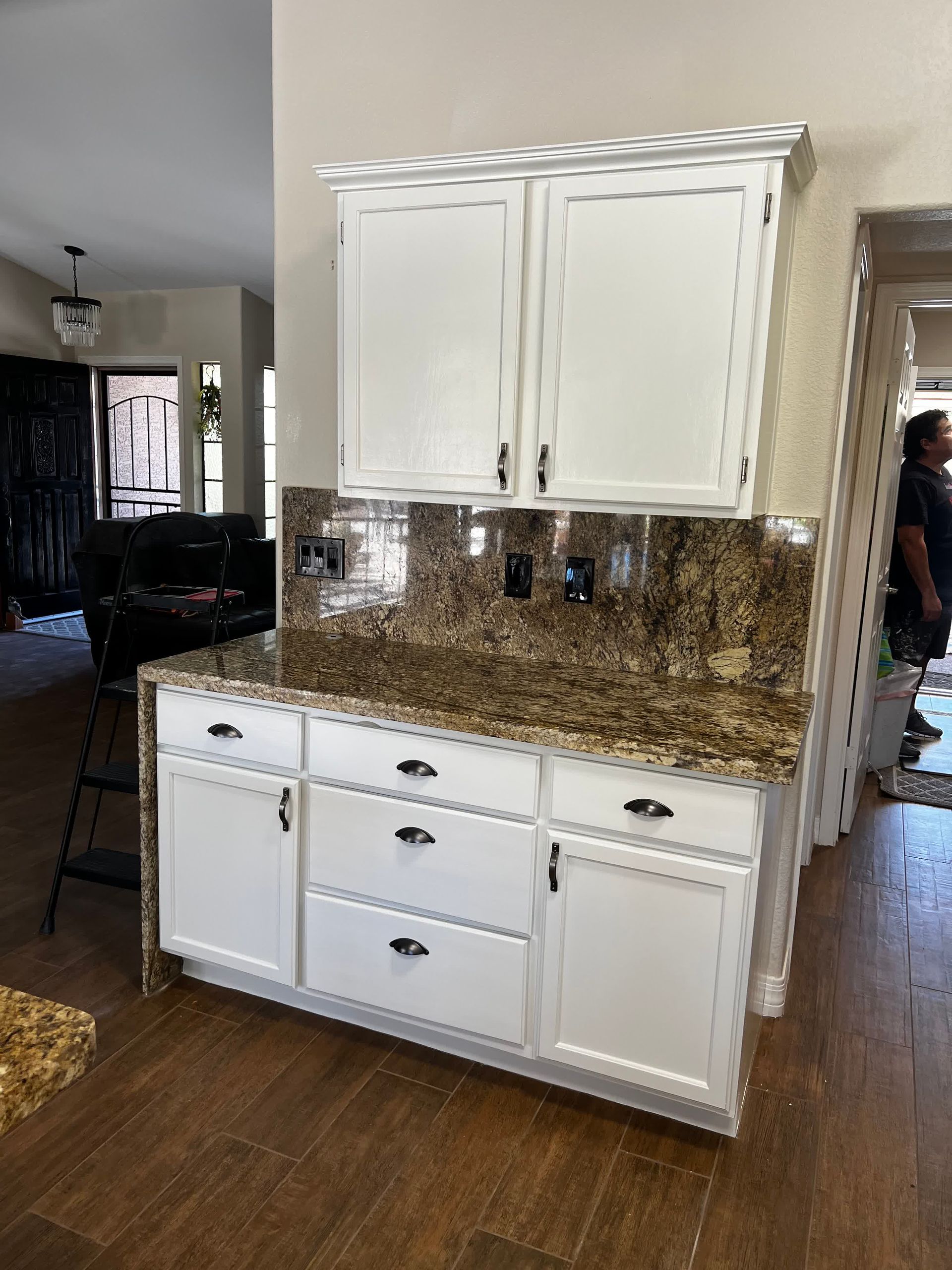 A kitchen with white cabinets and granite counter tops.