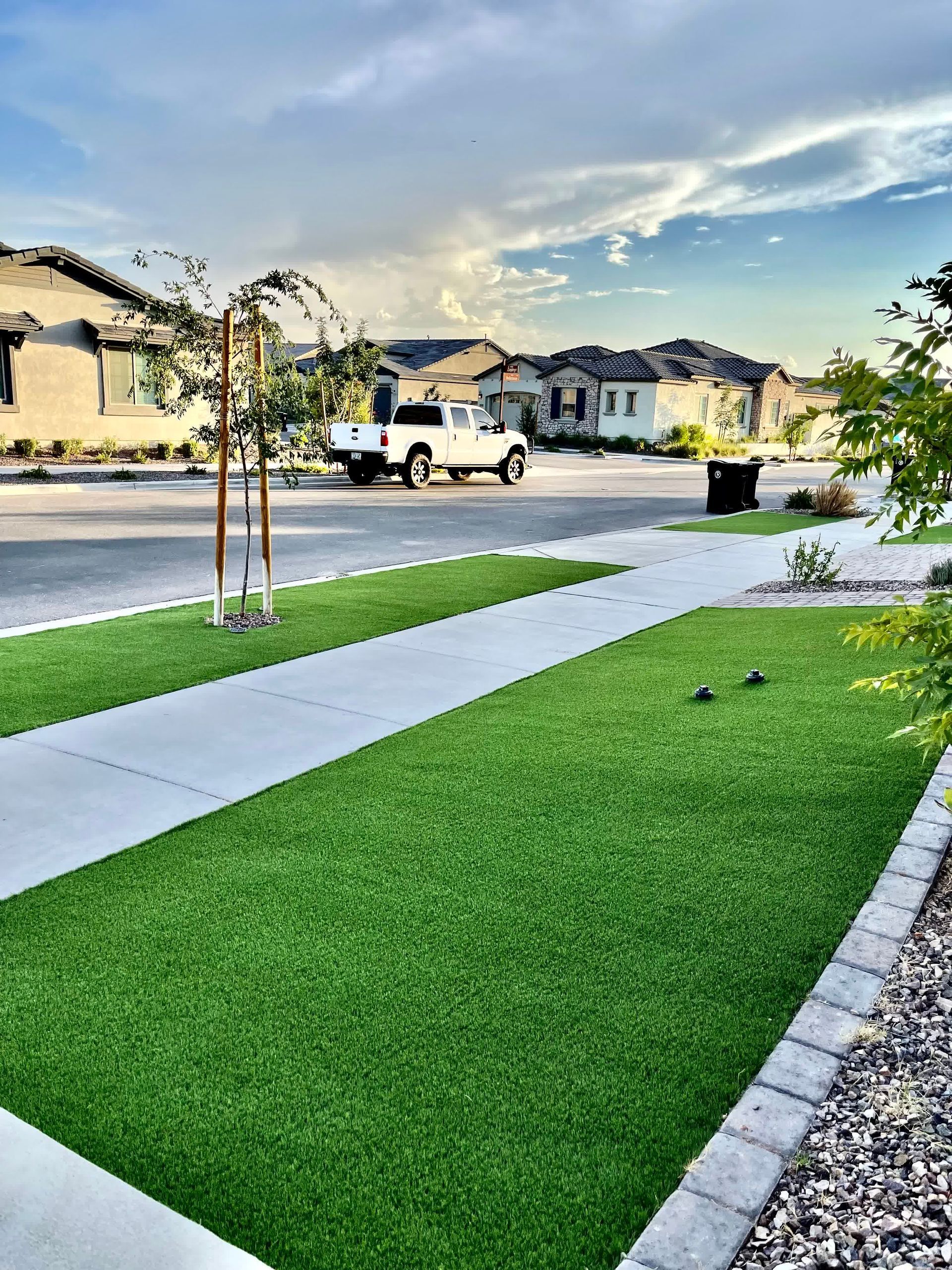 A white truck is parked on the side of the road next to a lush green lawn.