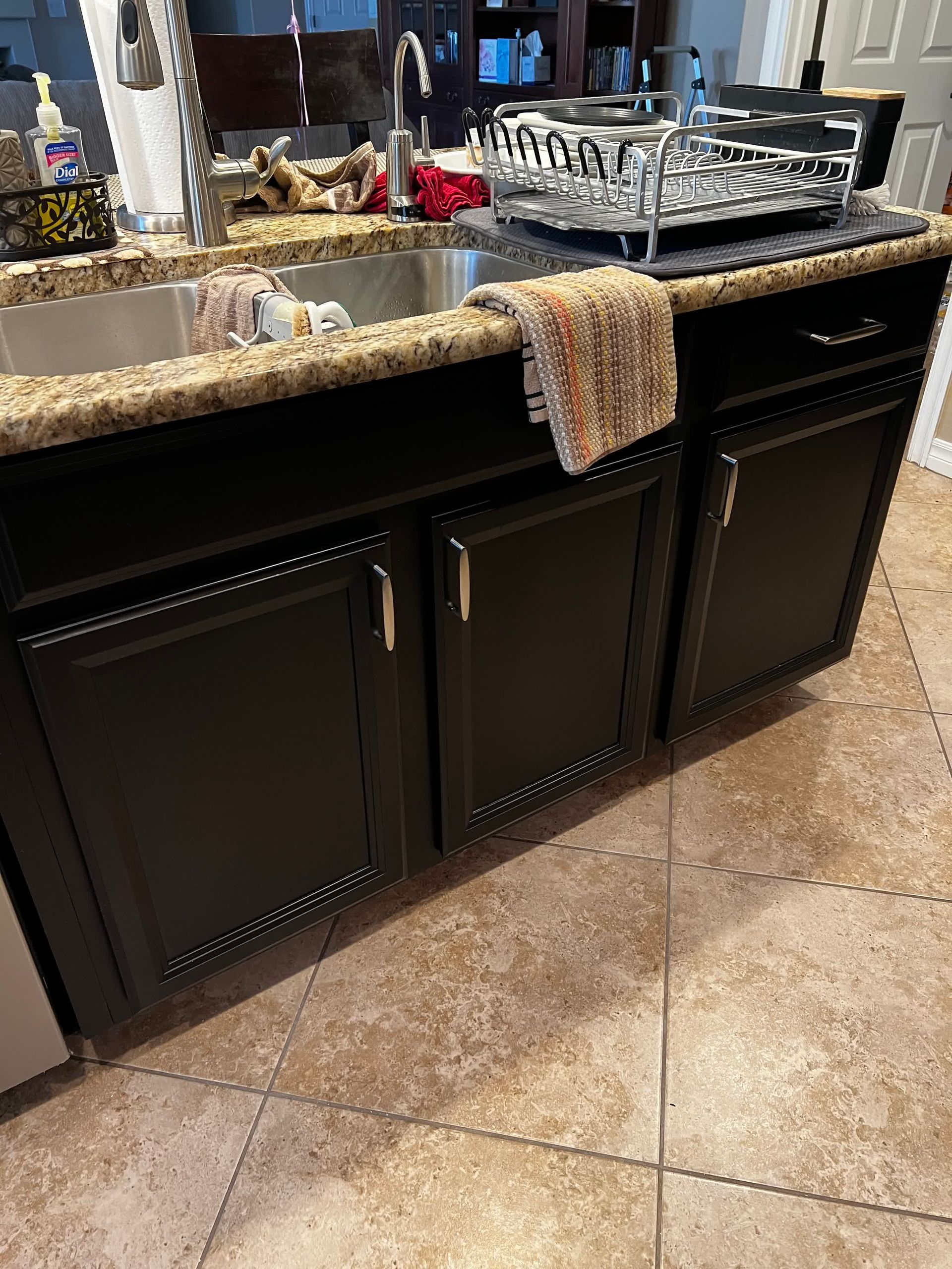 A kitchen sink with black cabinets and granite counter tops.
