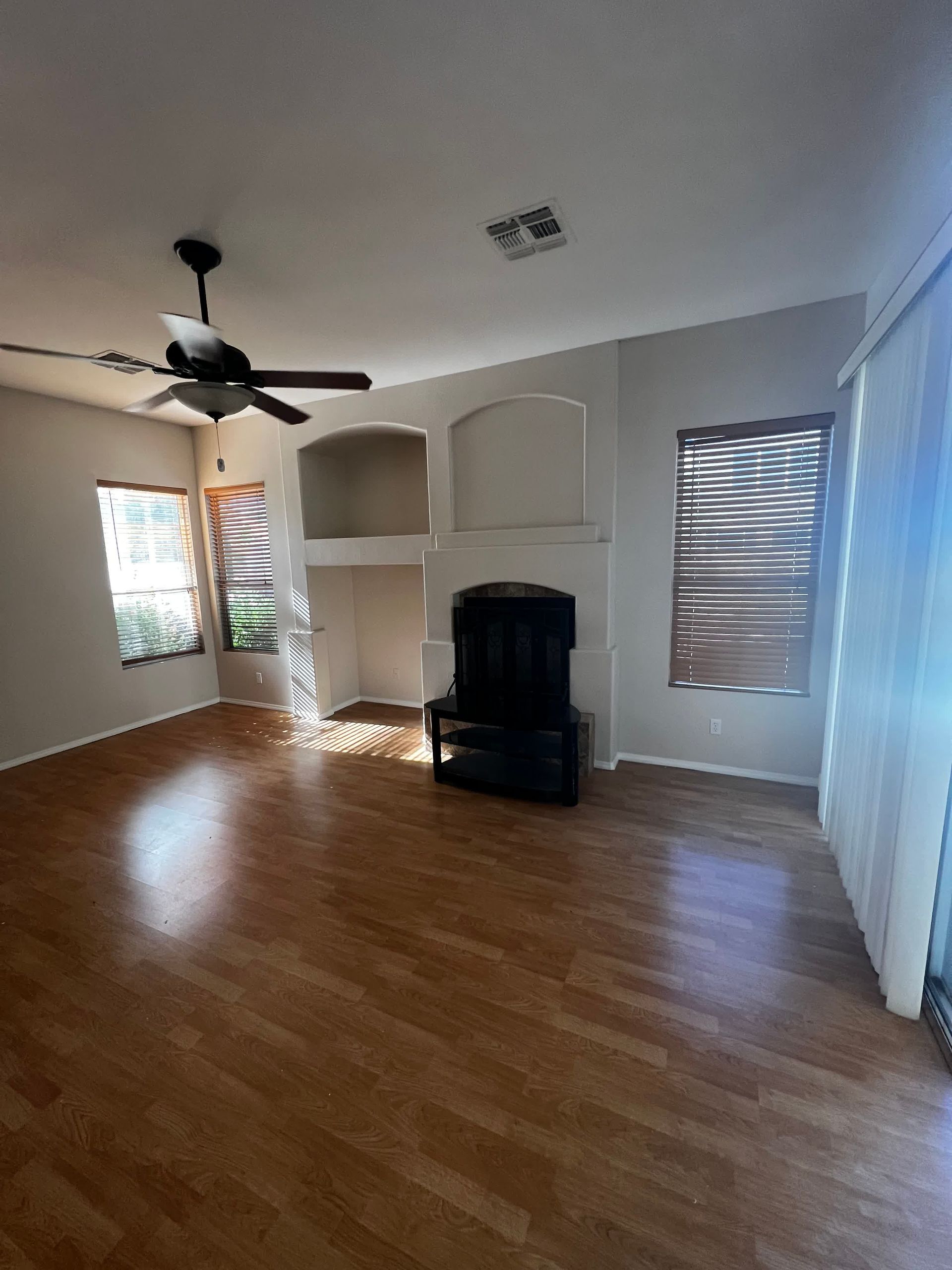 An empty living room with hardwood floors and a ceiling fan.