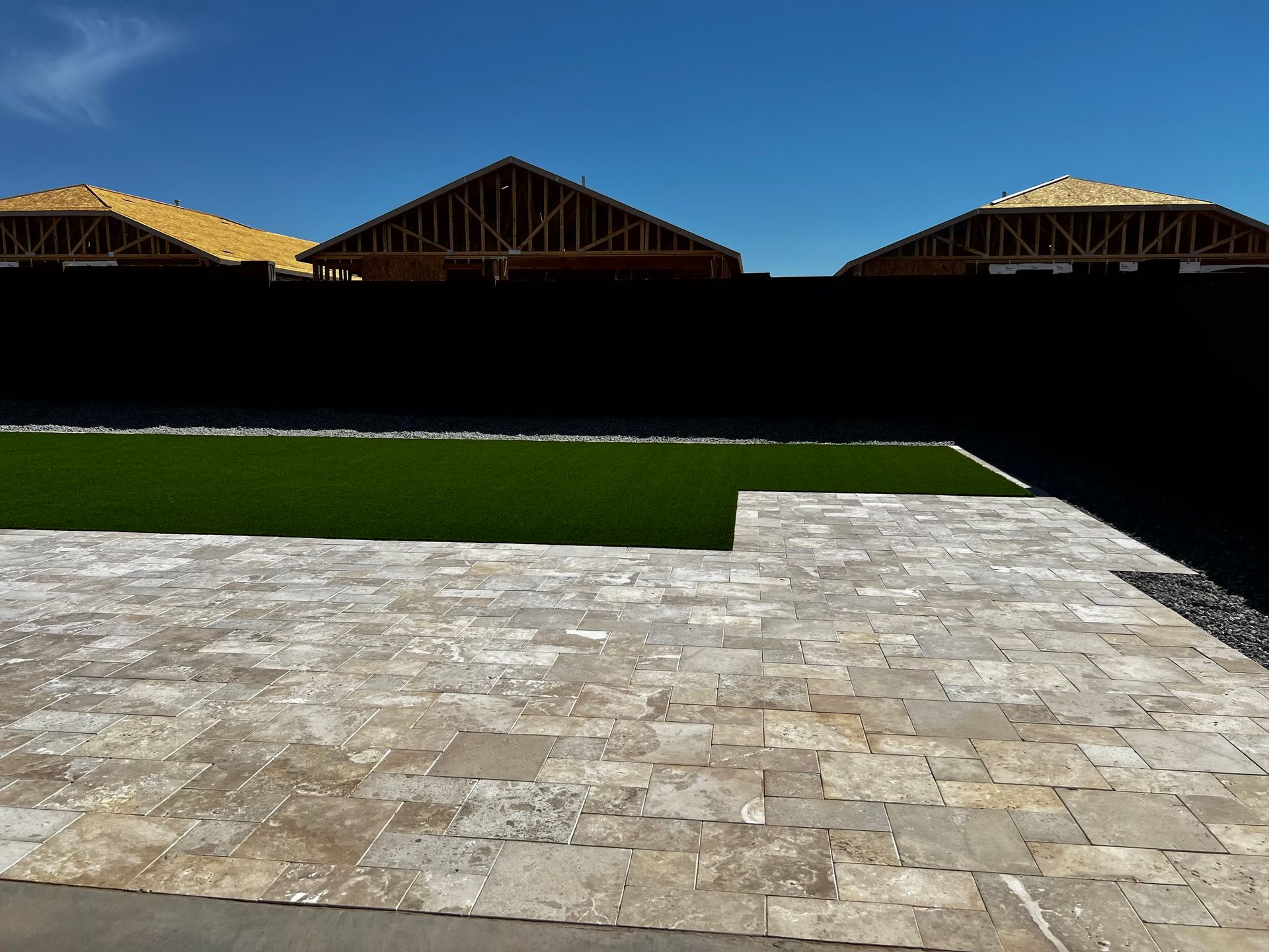 A brick walkway leading to a grassy area with houses in the background