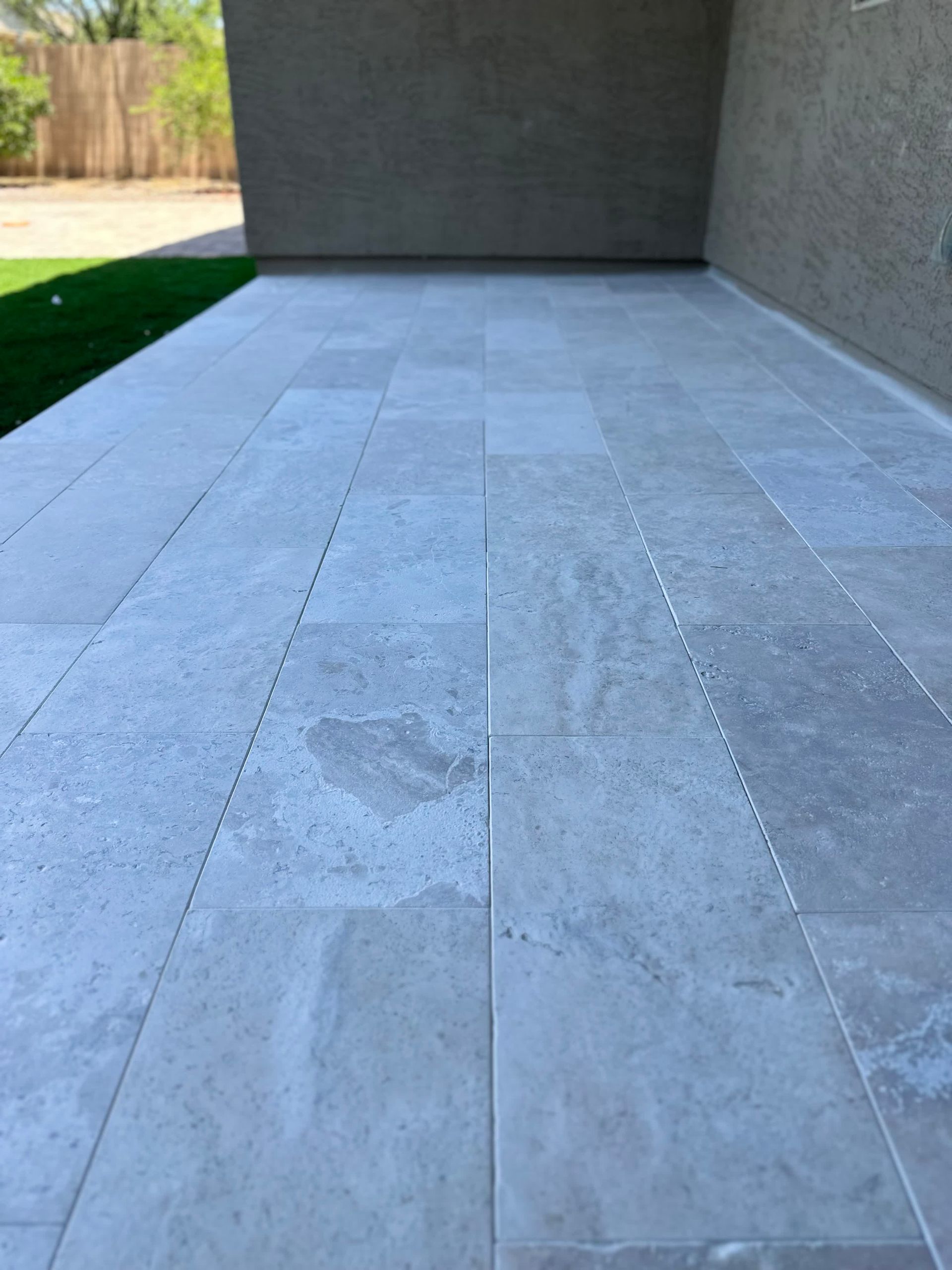 A patio with a lot of tiles on it and a fence in the background.