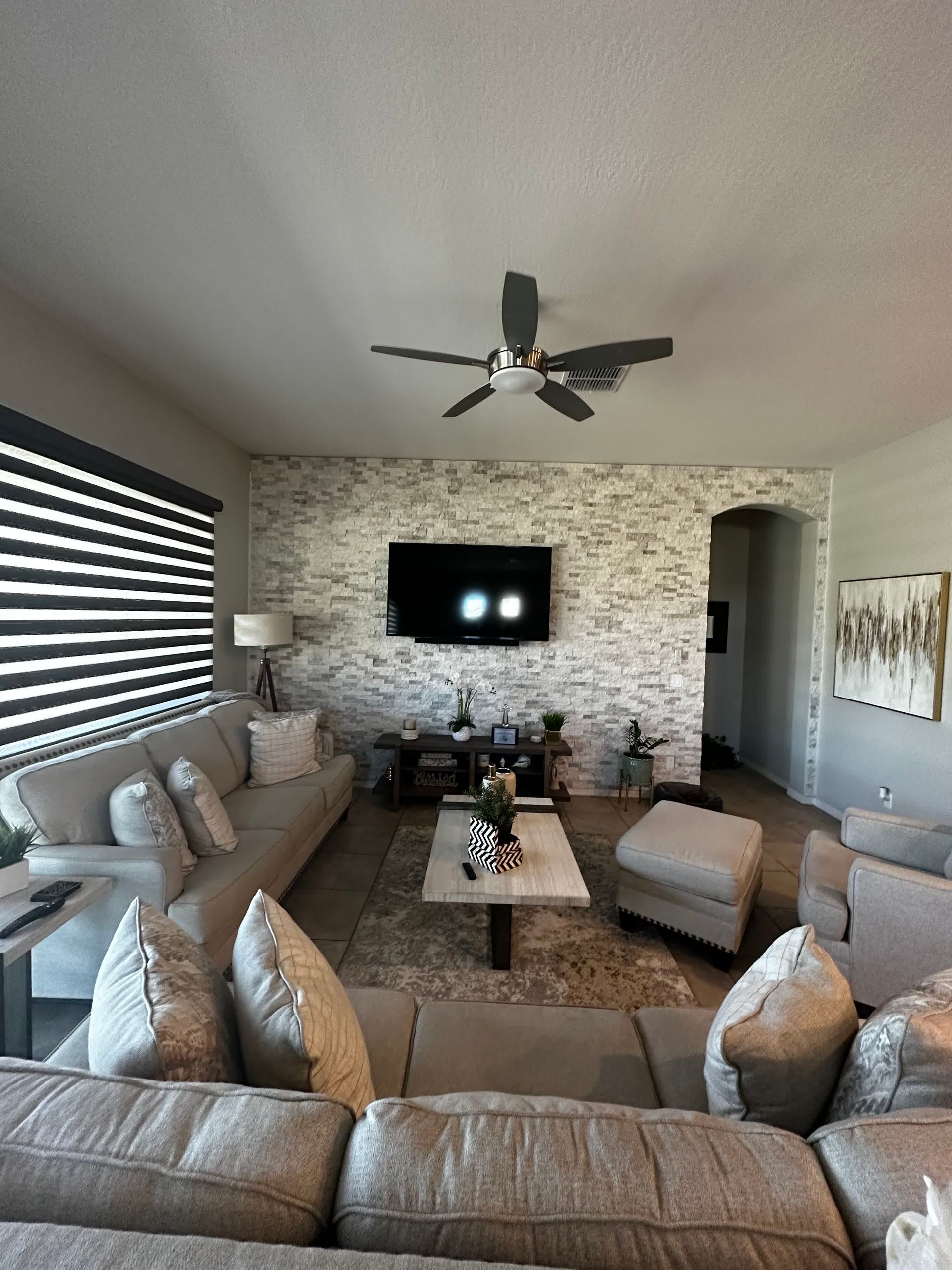 A living room with a ceiling fan and a flat screen tv