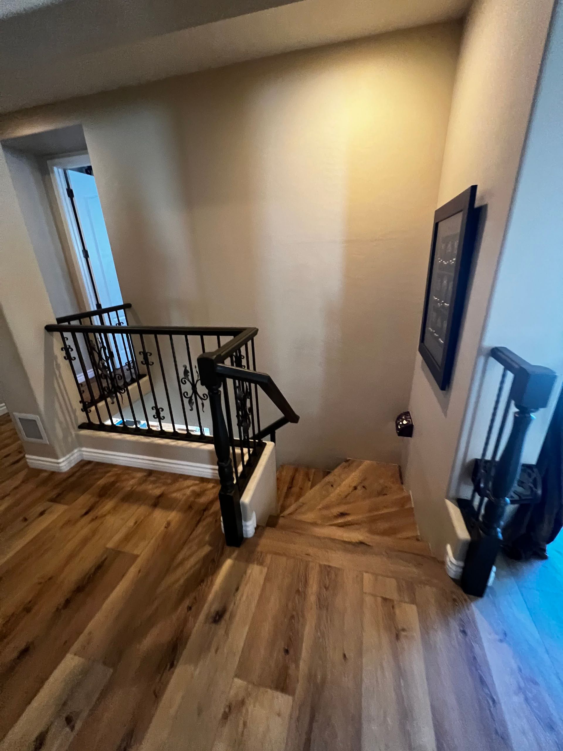 A staircase with a wrought iron railing and wooden floors in a house.