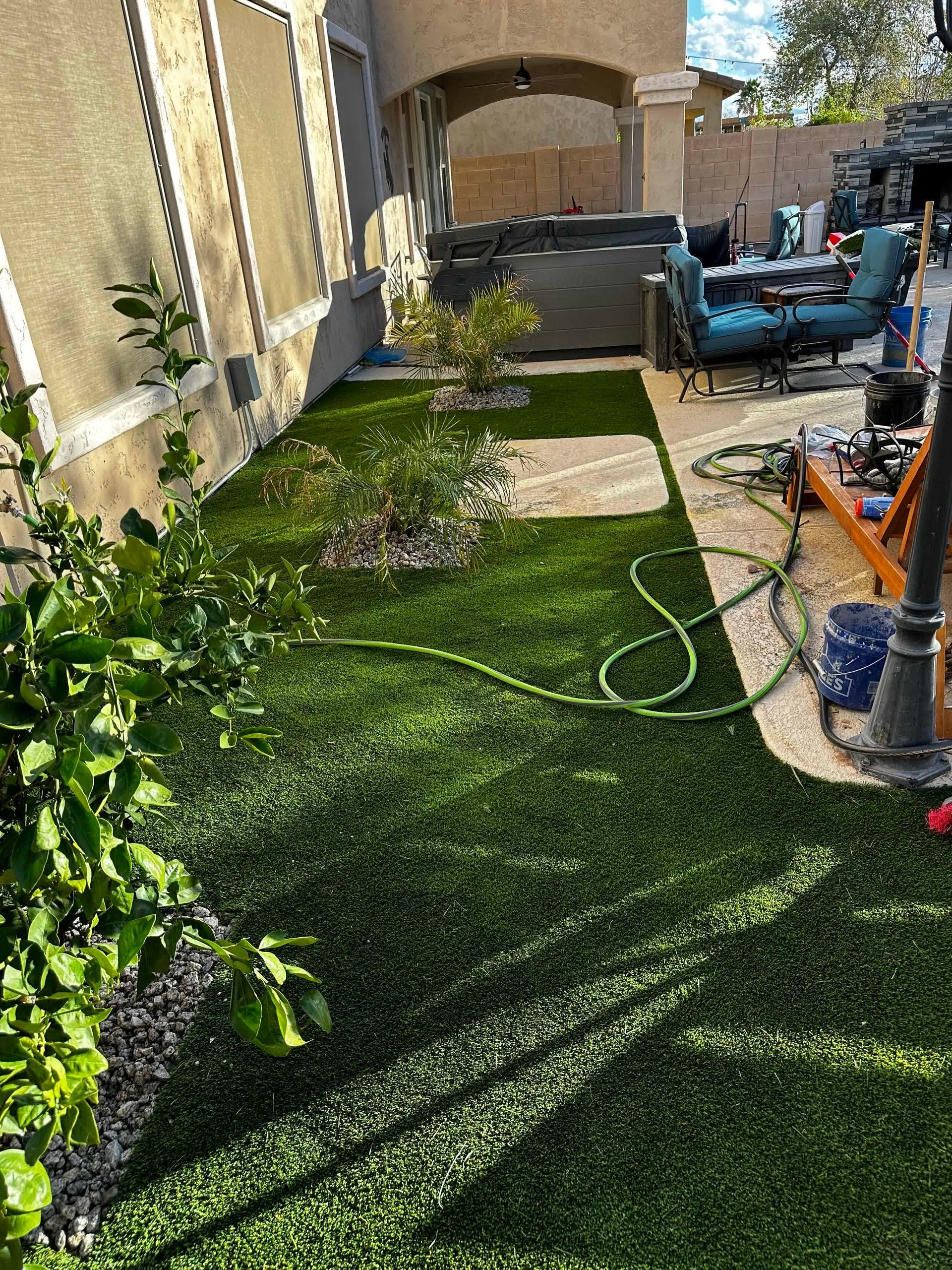A backyard with a lot of grass and a hose.