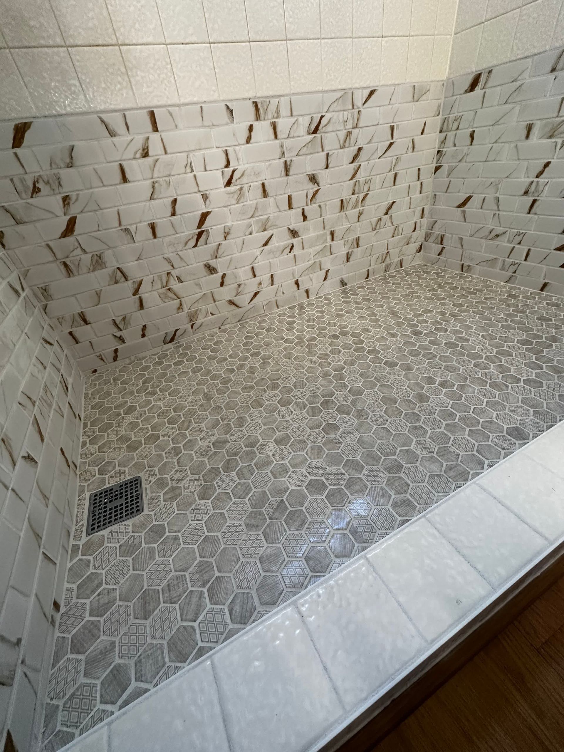 A walk in shower with a tiled floor and walls.