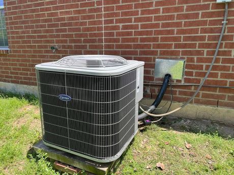 An air conditioner is sitting outside of a brick building.