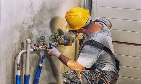 A man wearing a hard hat is working on a pipe.