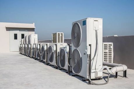 A row of air conditioners on the roof of a building.