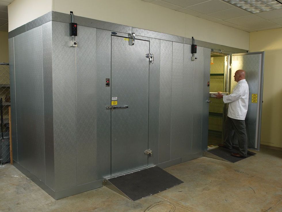 A man in a white shirt is standing in a large metal room.