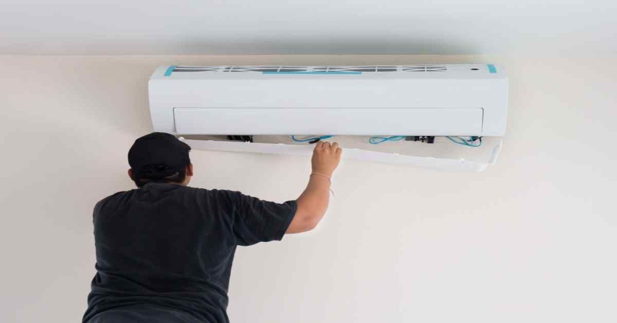 A man is installing an air conditioner on the wall.