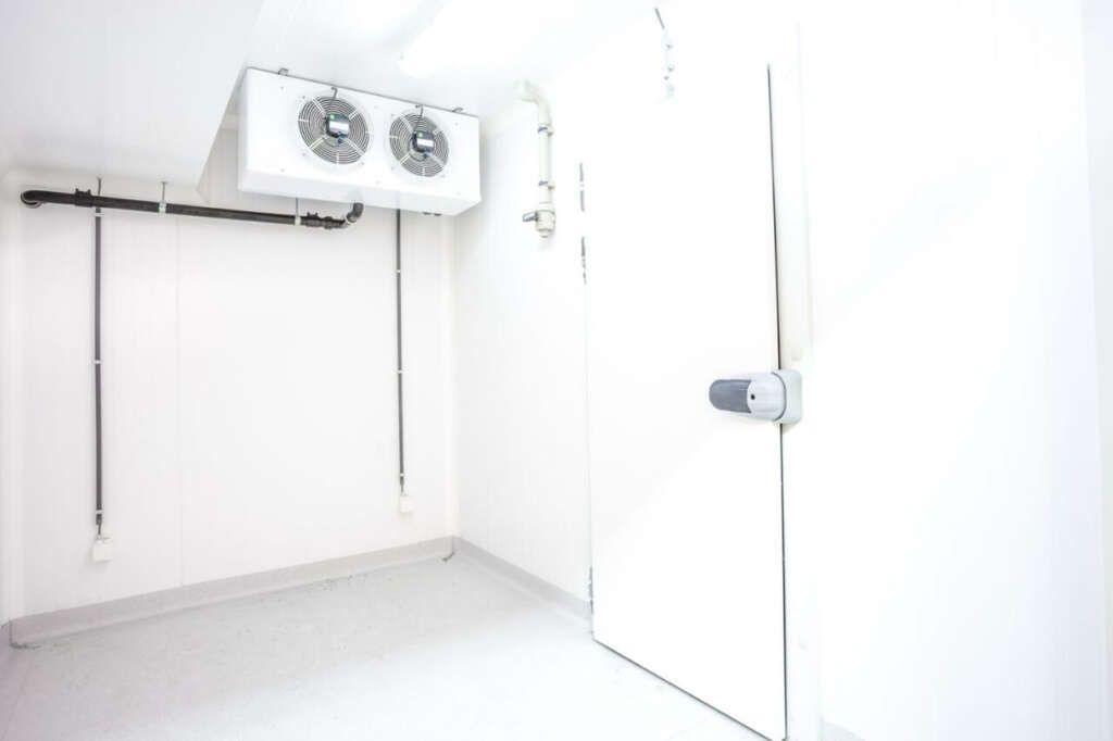 An empty room with a door and two fans on the ceiling.