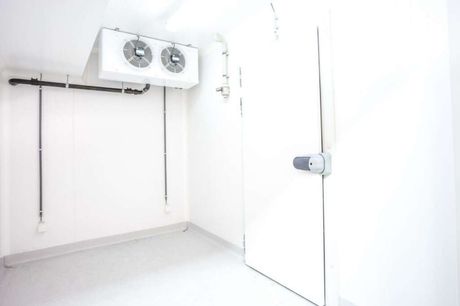 An empty room with a door and two fans on the ceiling.
