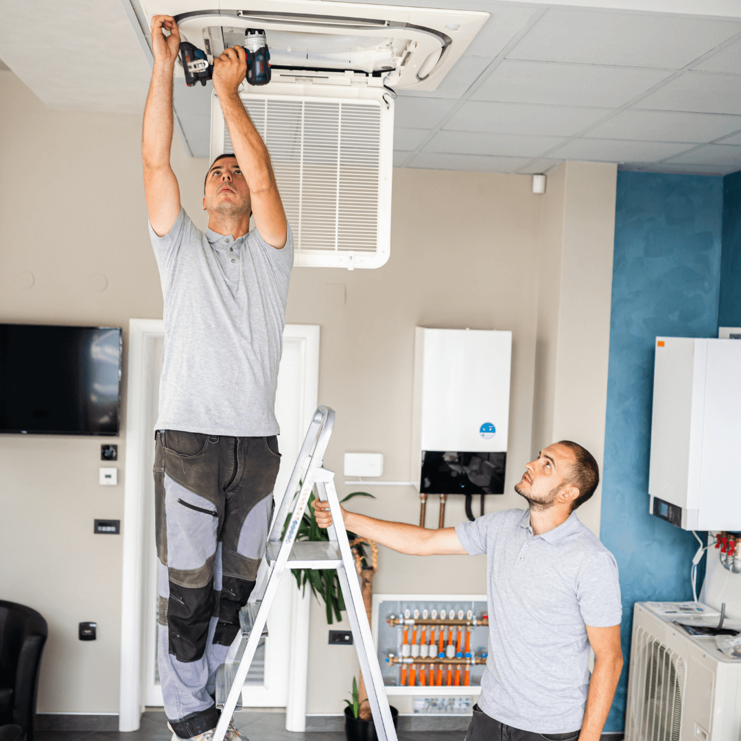 Two men are working on a ceiling fan in a living room.
