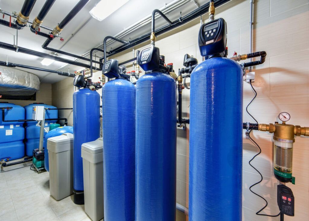 A row of blue water tanks are lined up in a room.