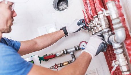 A plumber is working on a pipe in a bathroom.