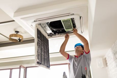 A man is working on an air conditioner in a room.
