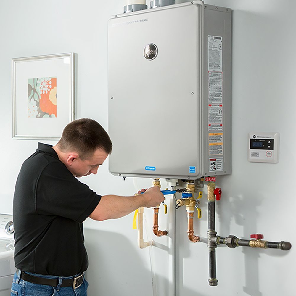 A man is working on a water heater in a bathroom