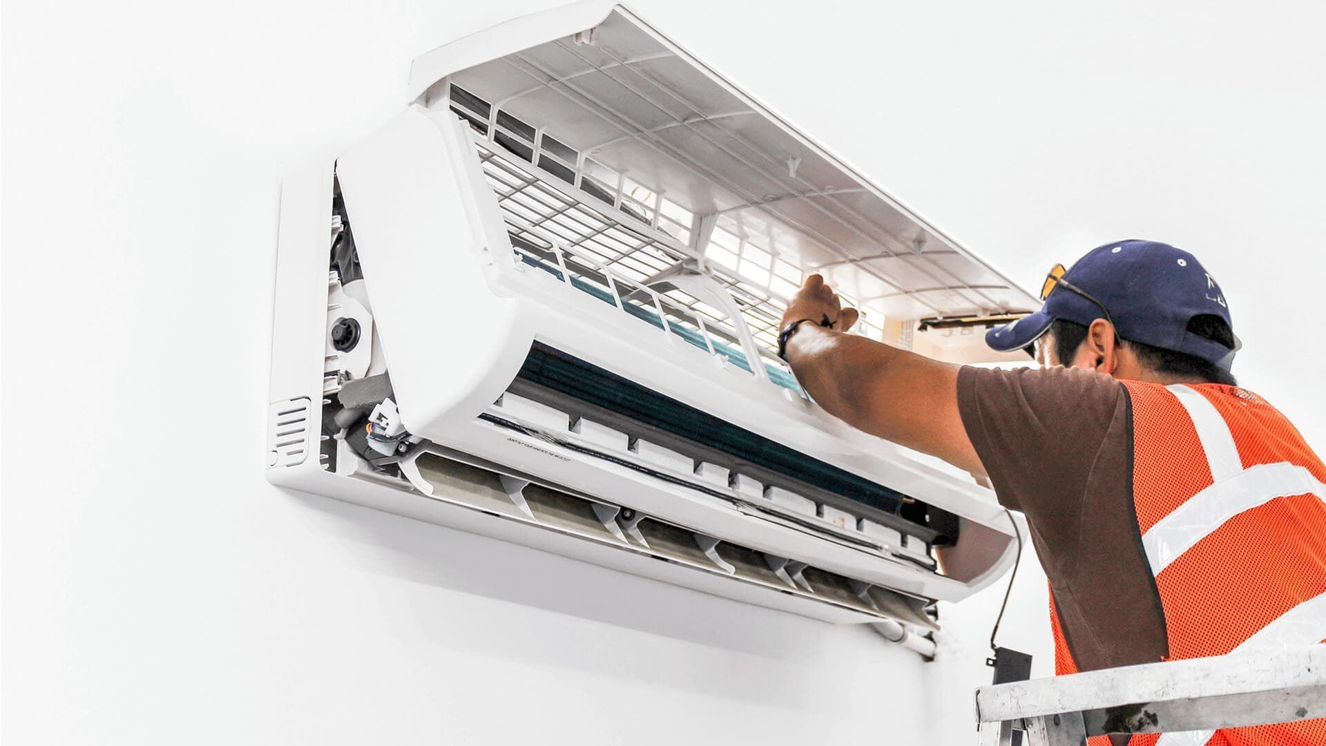 A man is working on a wall mounted air conditioner.