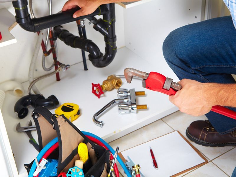 A man is fixing a sink with a wrench