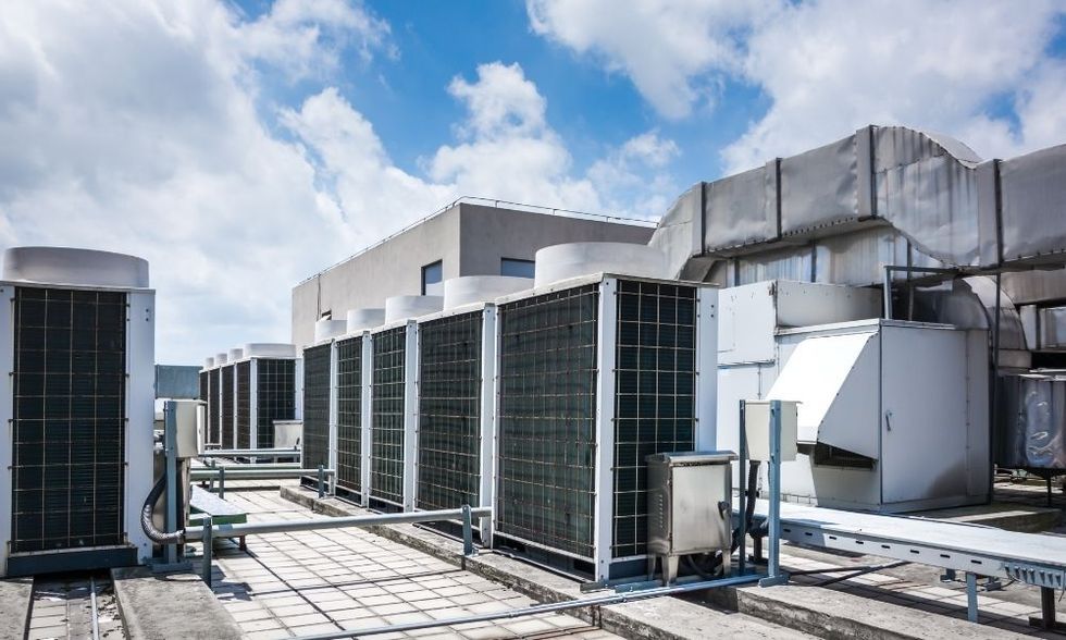 There are a lot of air conditioners on the roof of a building.