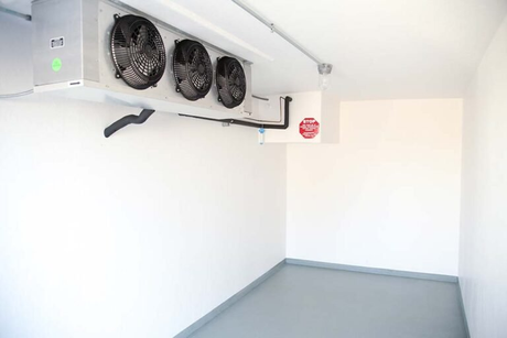 An empty room with three fans hanging from the ceiling.