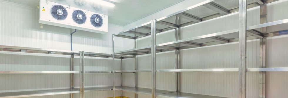 An empty refrigerator with stainless steel shelves and fans.